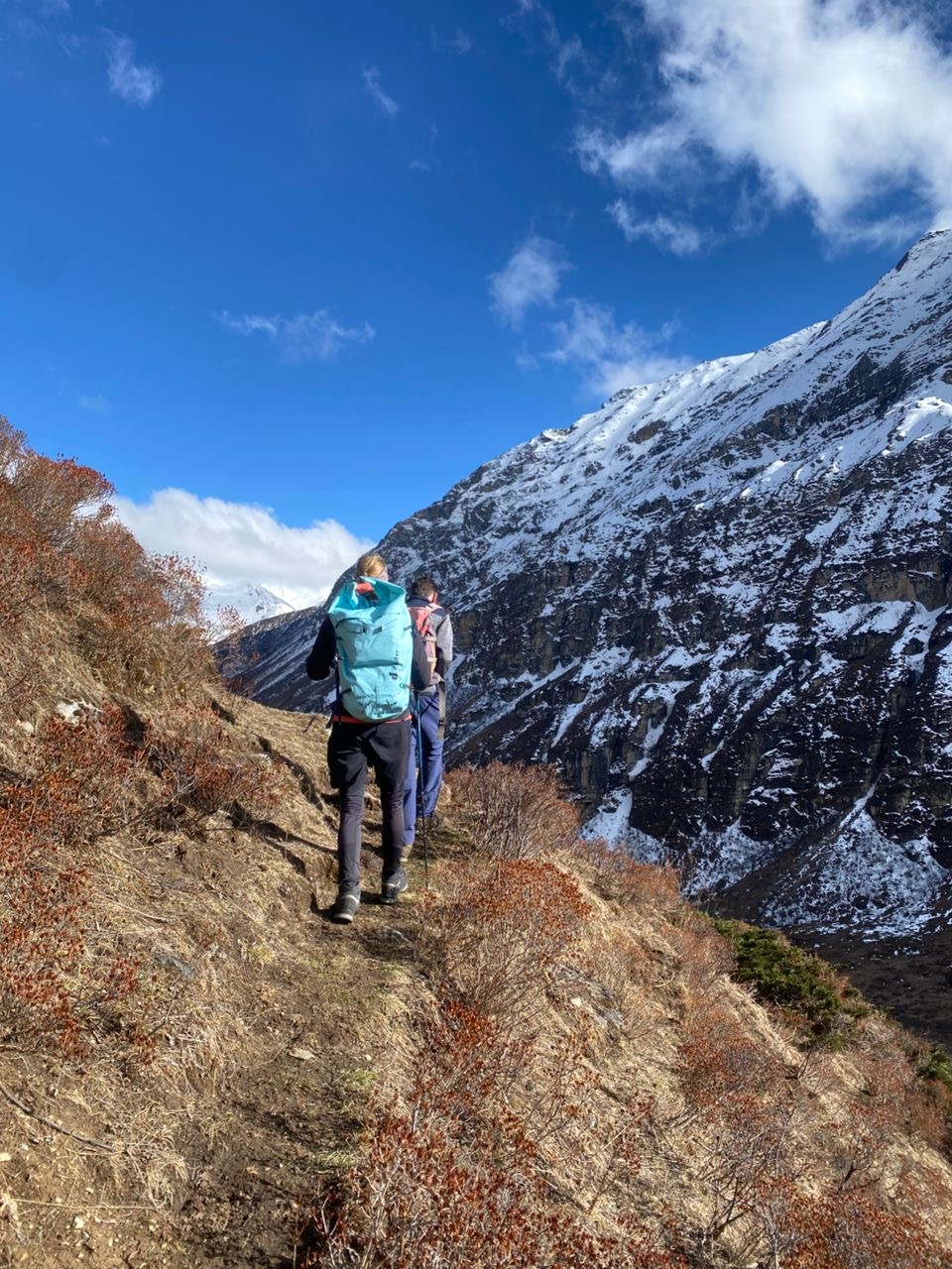 Hikers trekking along a mountain ridge with panoramic Himalayan views